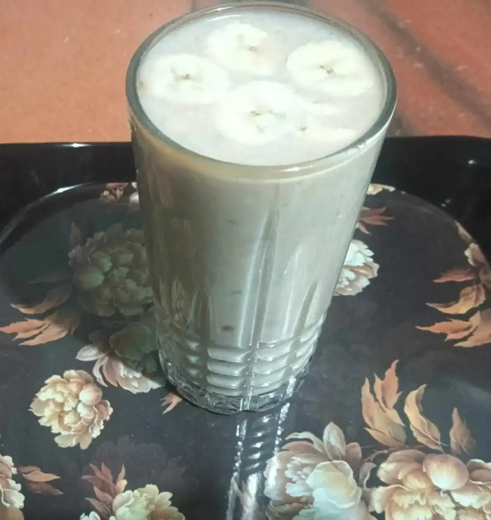 Creamy peanut butter banana smoothie topped with fresh banana slices in a glass