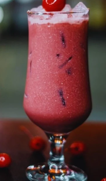 Protein-packed tart cherry juice smoothie served in a glass with ice and fresh cherry garnish