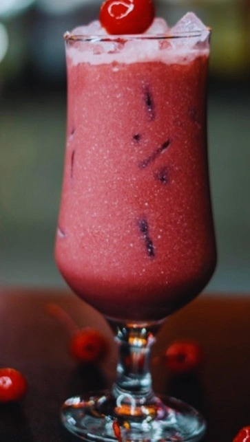 Protein-packed tart cherry juice smoothie served in a glass with ice and fresh cherry garnish