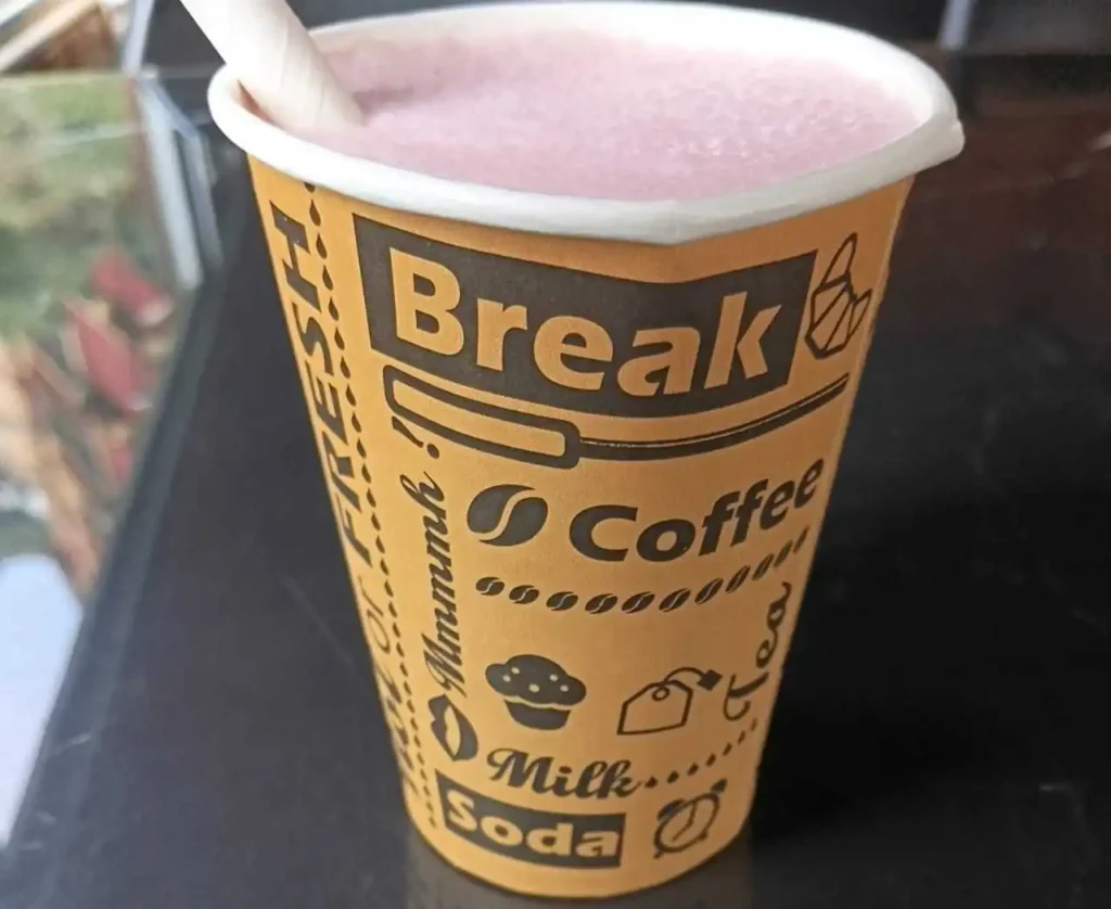 A glass of freshly blended strawberry smoothie with fresh strawberries on the side