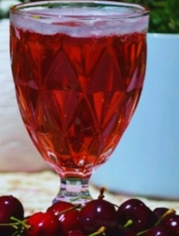 Glass of fresh tart cherry juice with whole cherries, healthy antioxidant-rich drink