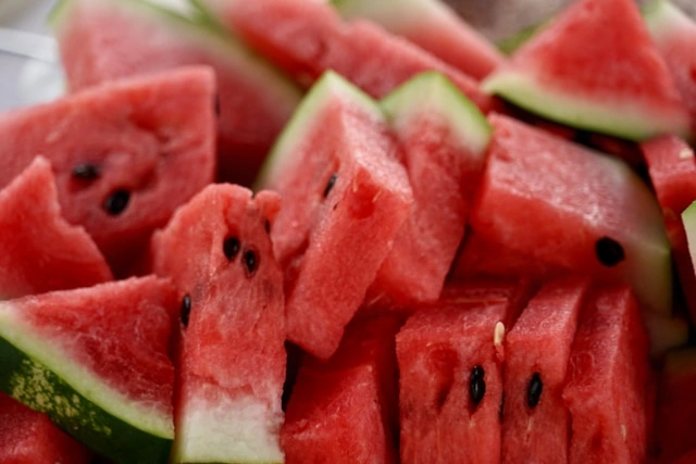 A close-up shot of freshly sliced red watermelon pieces with black seeds, showing the juicy texture of the fruit.