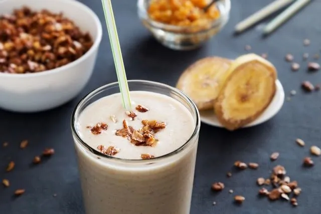 A glass of creamy Almond Butter Date and Banana Shake topped with crunchy almond bits, perfect for a healthy breakfast or post-workout recovery.